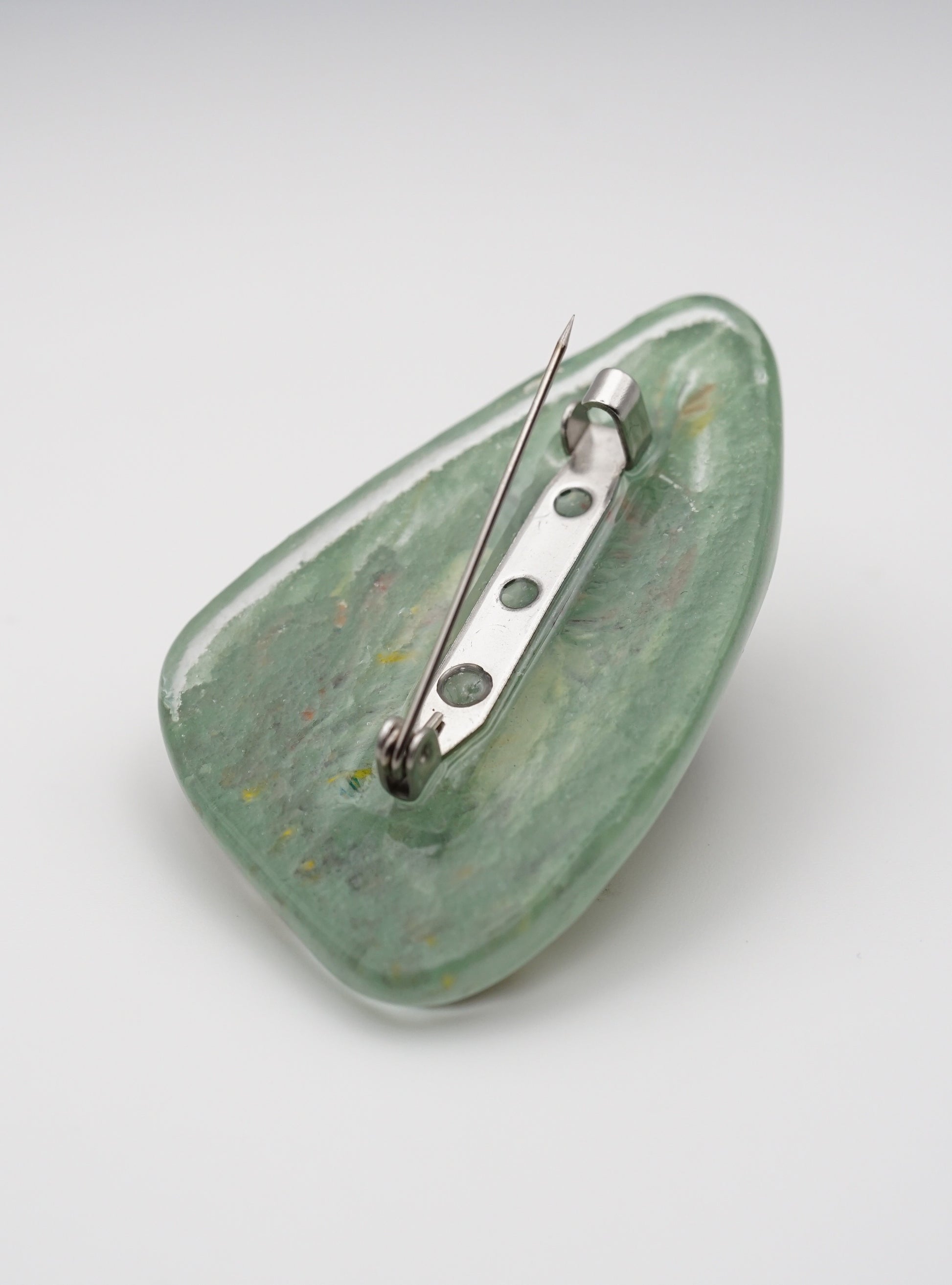 Green glass with a metal pin on a white background
