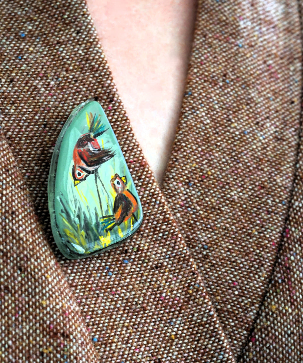 Hand-painted brooch with birds on a textured fabric background